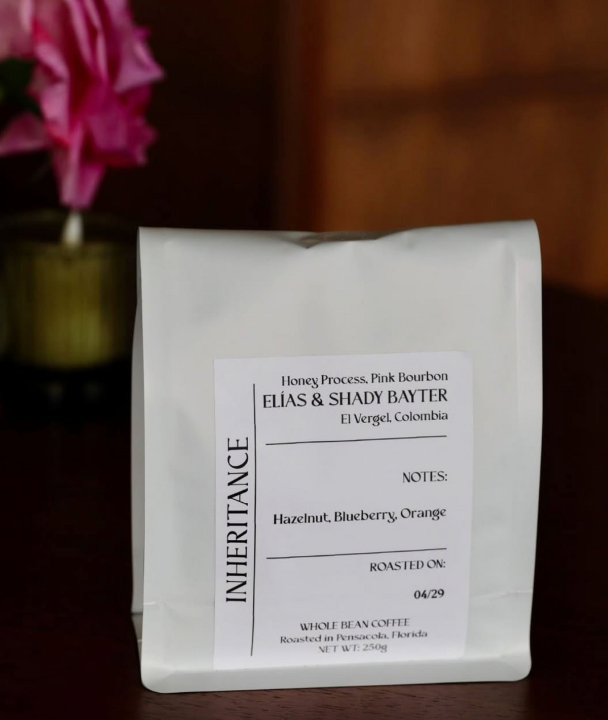 Bag of Inheritance single-origin coffee beside flowers - coffee subscription roasted fresh in Pensacola, FL