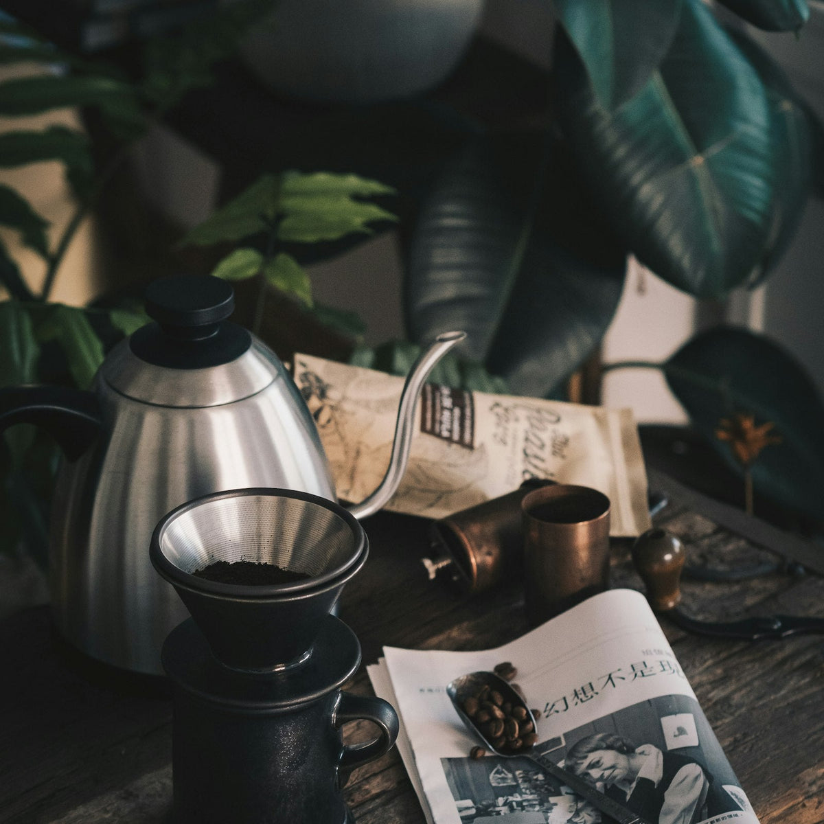 A black single-dose burr grinder on a kitchen counter beside a stainless steel kettle