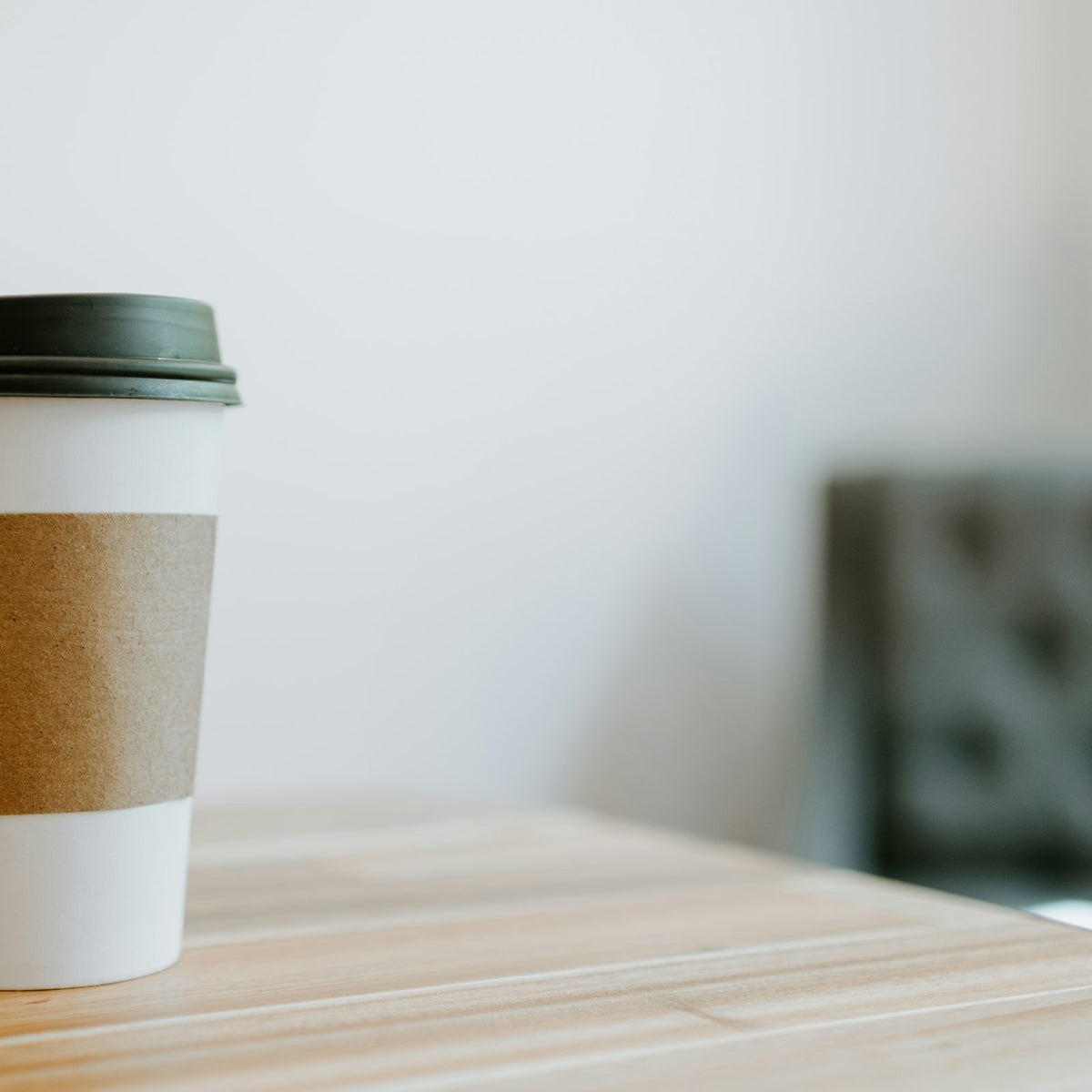 A white and brown takeaway paper coffee cup with a cardboard sleeve