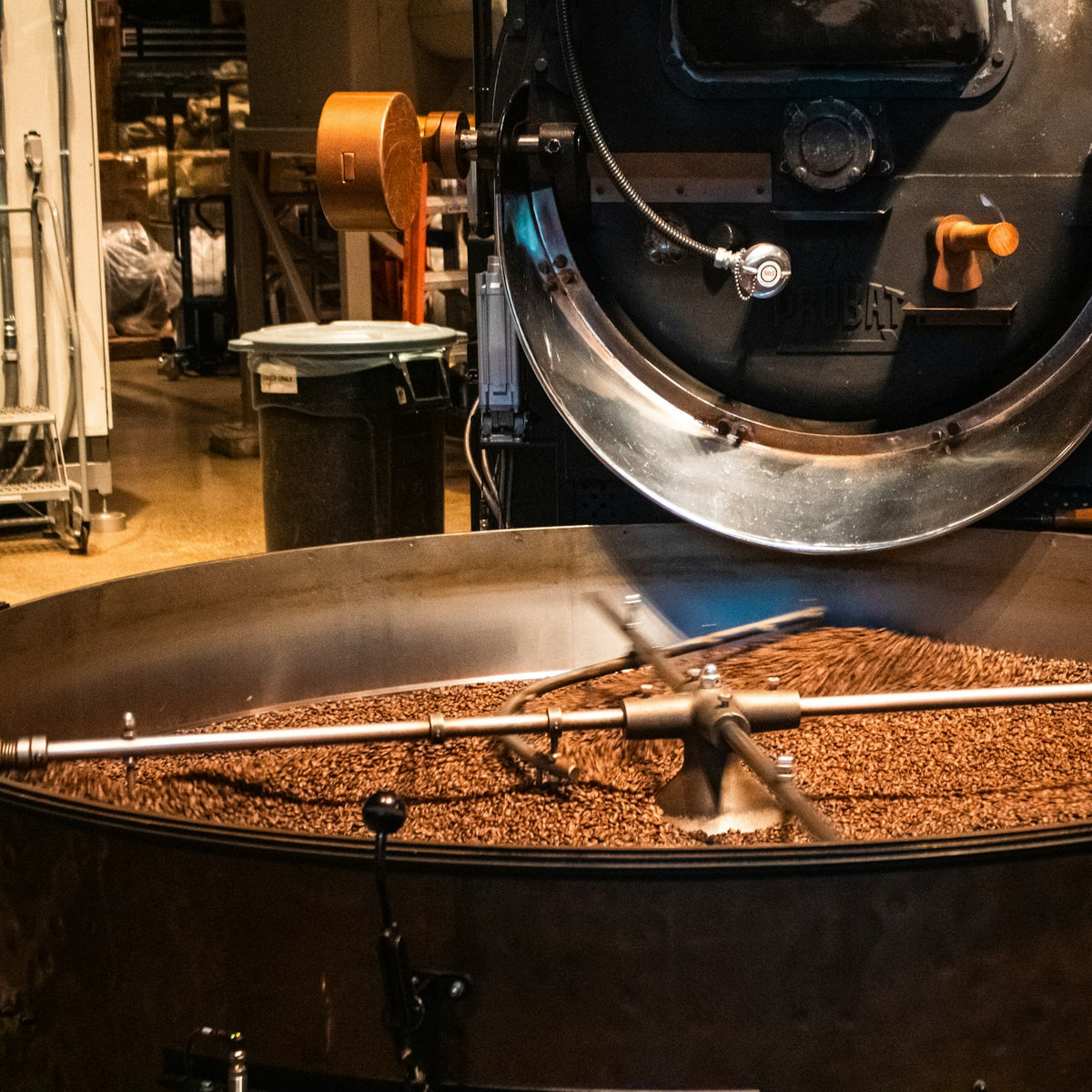 Rotating metal arms stirring freshly roasted coffee beans in a cooling tray