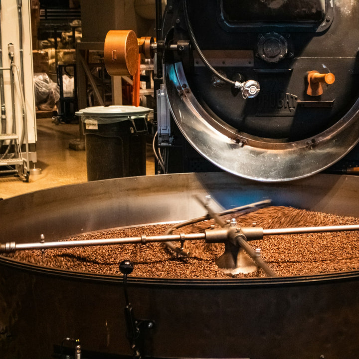 Rotating metal arms stirring freshly roasted coffee beans in a cooling tray