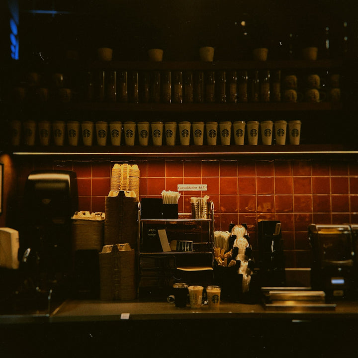 A coffee brewing machine and stacked cups on a commercial coffee shop service counter - Inheritance Coffee, Pensacola, FL roaster for cafes, churches and coffee startups