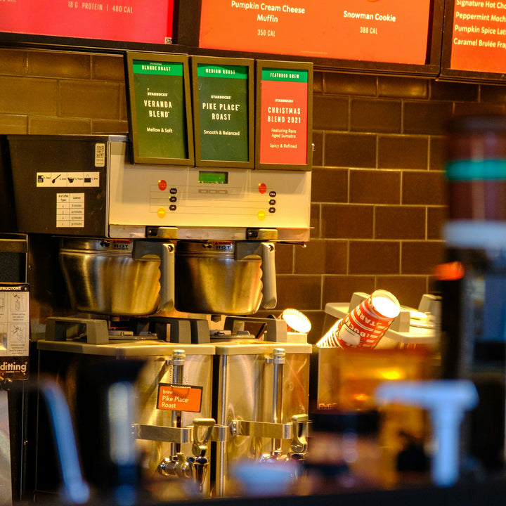 A self-serve coffee counter with beverage dispensers and stacked cups