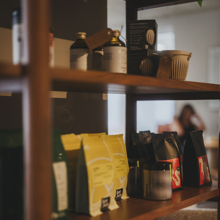 Retail shelves in a coffee shop stocked with bags of coffee and glass jars