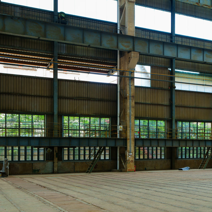 An empty light industrial unit with a bare concrete floor and exposed steel beams, the kind of space a coffee roastery needs zoned for manufacturing