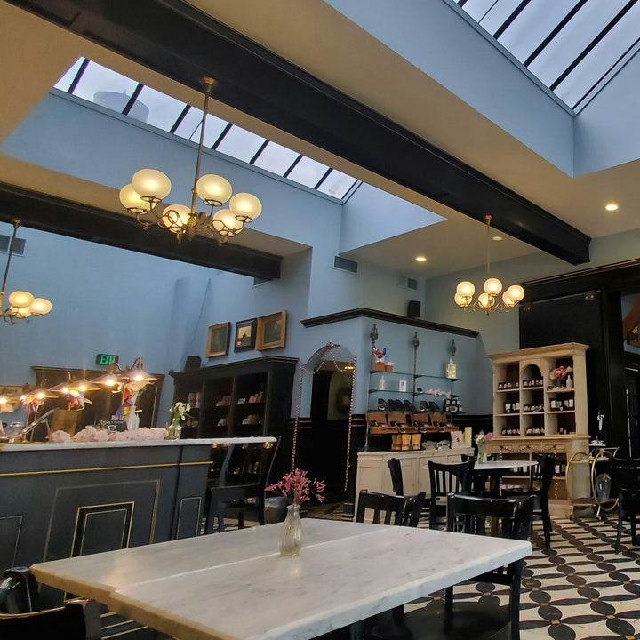 A quiet cafe room with a service counter, checkered floor and empty seating under a skylight - Inheritance Coffee, Pensacola, FL church coffee consulting