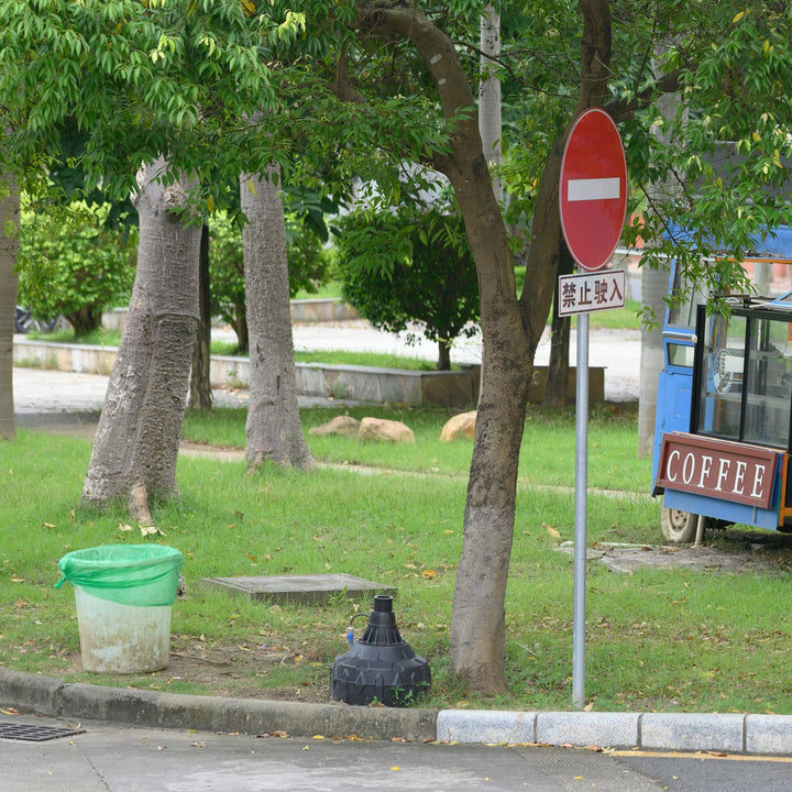 A blue mobile coffee cart parked on a grassy lawn beside a road