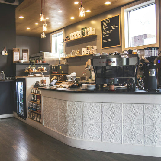 Espresso machines and brewing equipment lined up along a coffee shop counter before opening