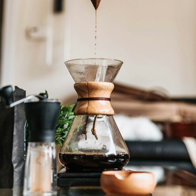A hand filtering coffee into a funnel-shaped pour-over dripper