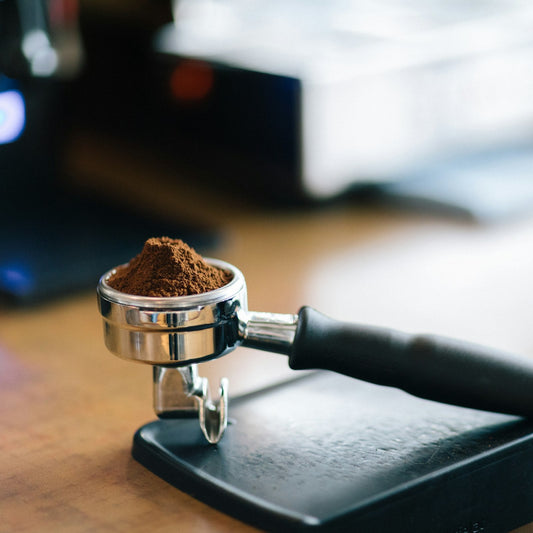 Portafilter holding a weighed dose of ground coffee resting on a bar scale