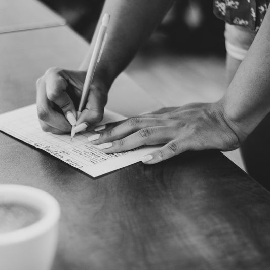 A hand writing cupping scores on a paper form during a coffee evaluation session