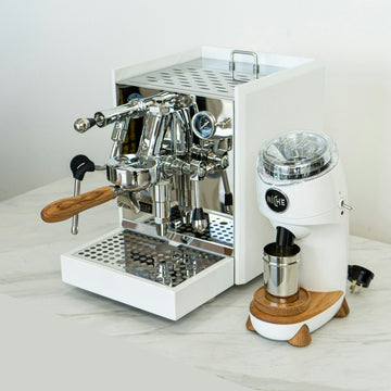 Grey commercial espresso machine and grinder on the white counter of a specialty coffee shop bar