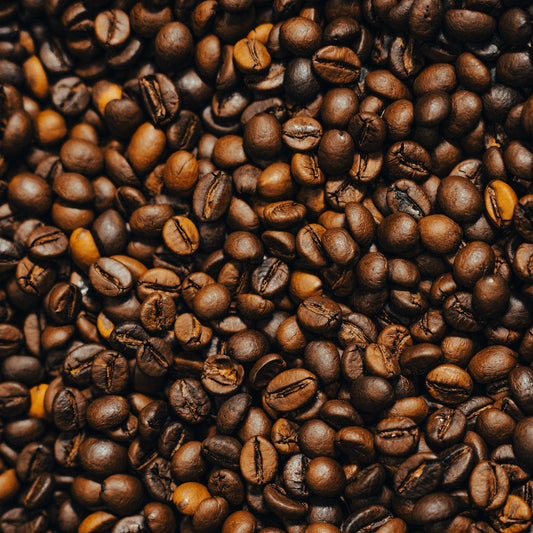 A dense pile of roasted coffee beans filling the frame, showing the surface texture of each bean - Inheritance Coffee, Pensacola, FL roaster for home brewers and cafes