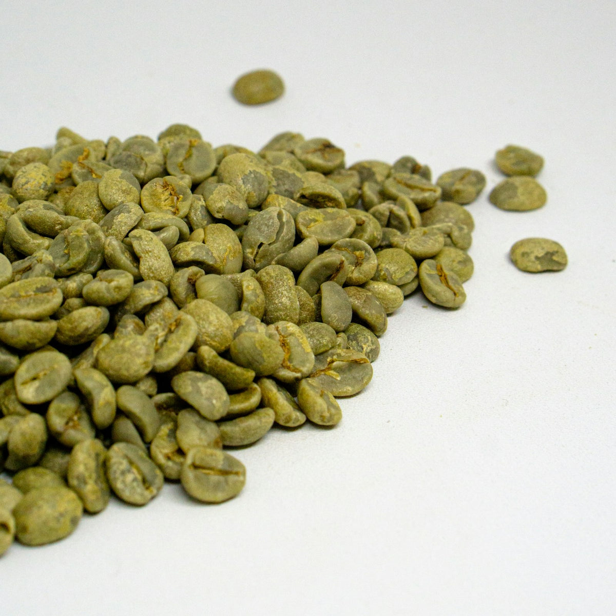 A pile of unroasted coffee beans on a white table