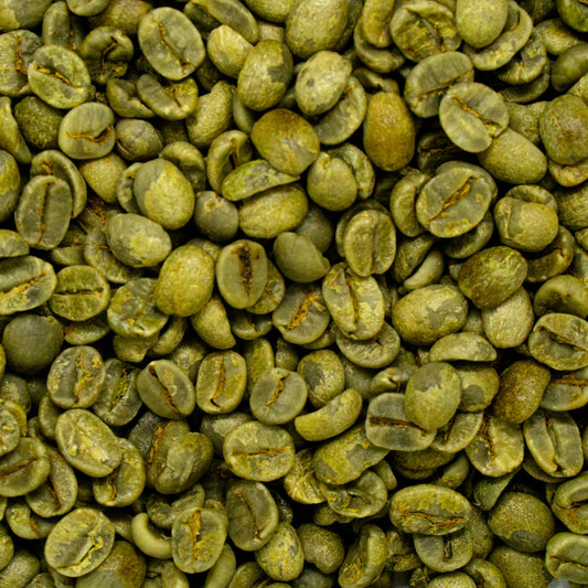 Raw green coffee beans piled on a table, the form coffee is in when it goes out for decaffeination