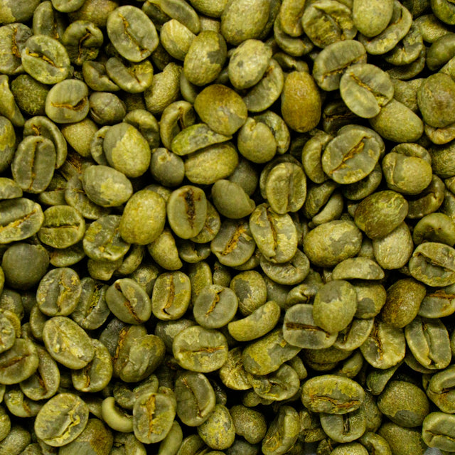 Raw green coffee beans piled on a table, the form coffee is in when it goes out for decaffeination
