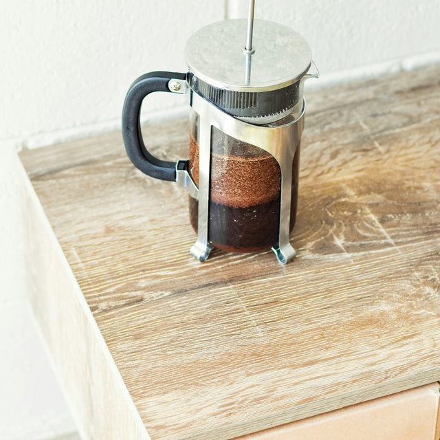 A French press coffee maker on a wooden table, the most common immersion coffee brewer