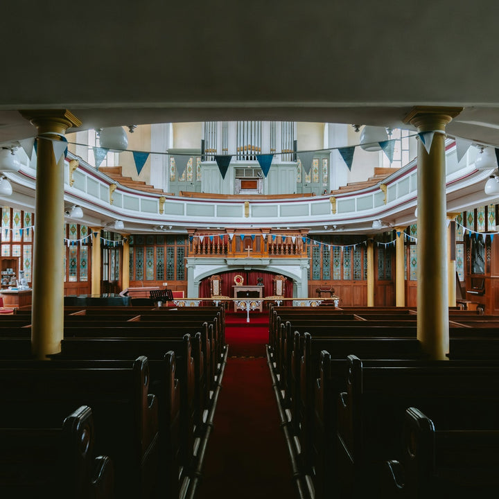 The interior of a church sanctuary with rows of wooden pews