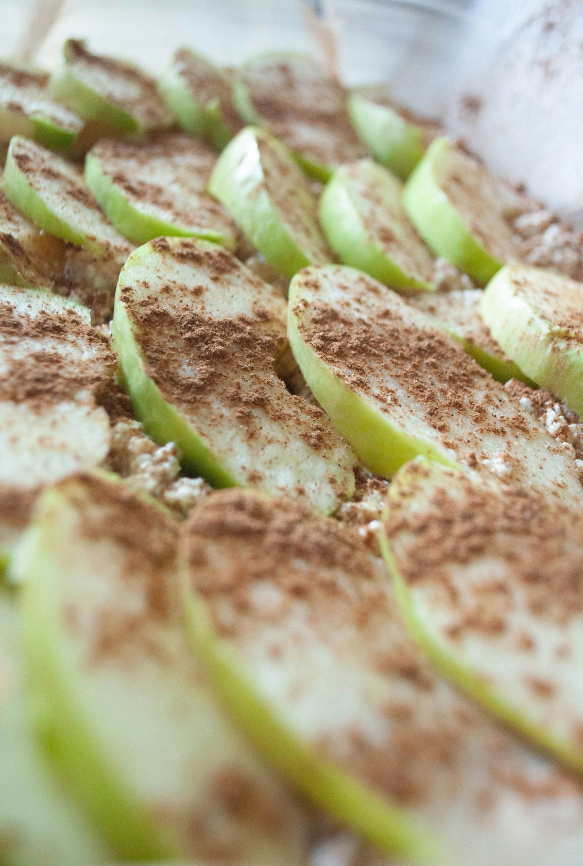 Sliced green apples sprinkled with cinnamon on a wooden board