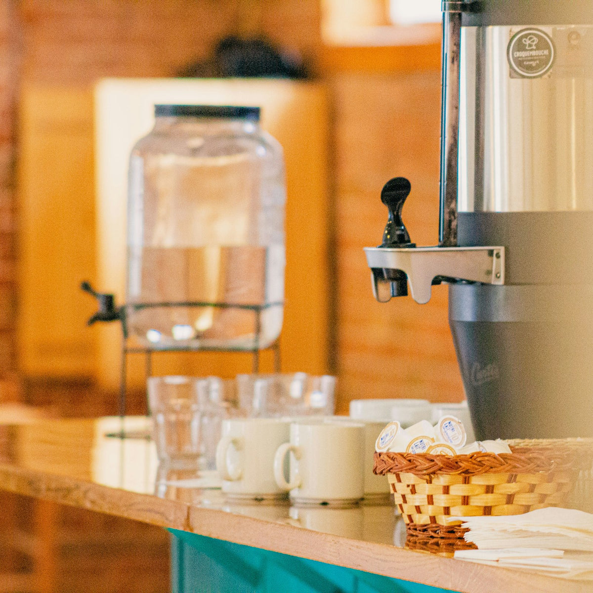 Coffee dispenser and hot water urn set out on a buffet table before service