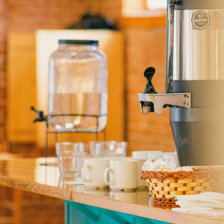 Coffee dispenser and hot water urn set out on a buffet table before service