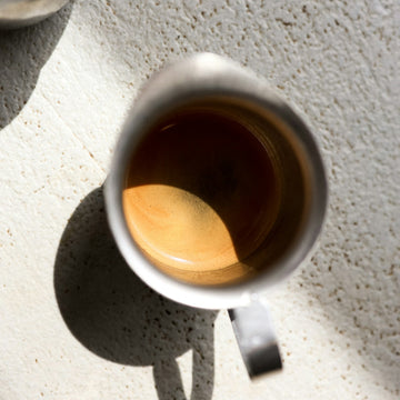 Two small metal cups of espresso side by side with a layer of golden crema across the surface