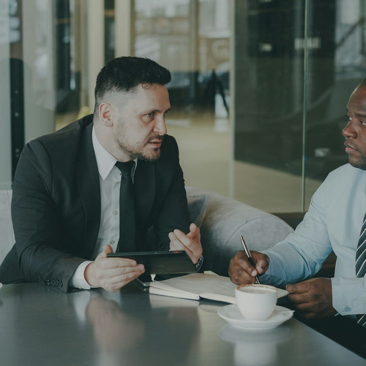 Two people reviewing a plan together over coffee at a table.