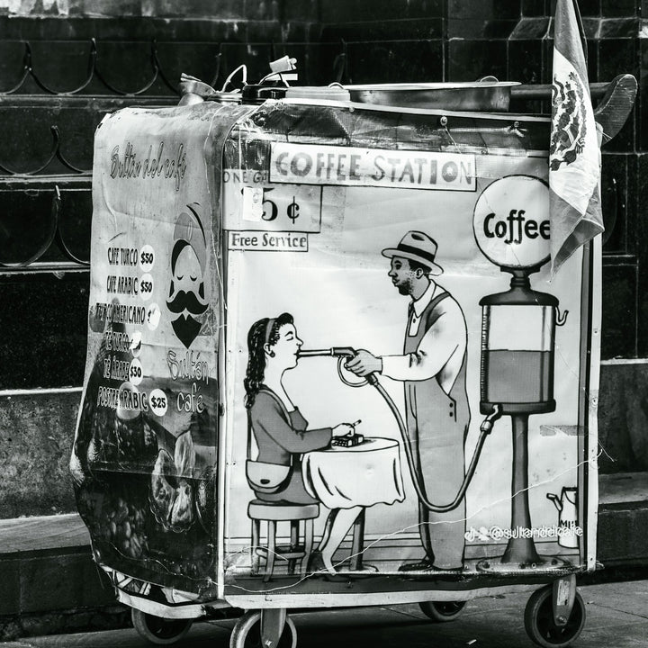 a vintage coffee cart painted with a colorful mural, set up as a street stand