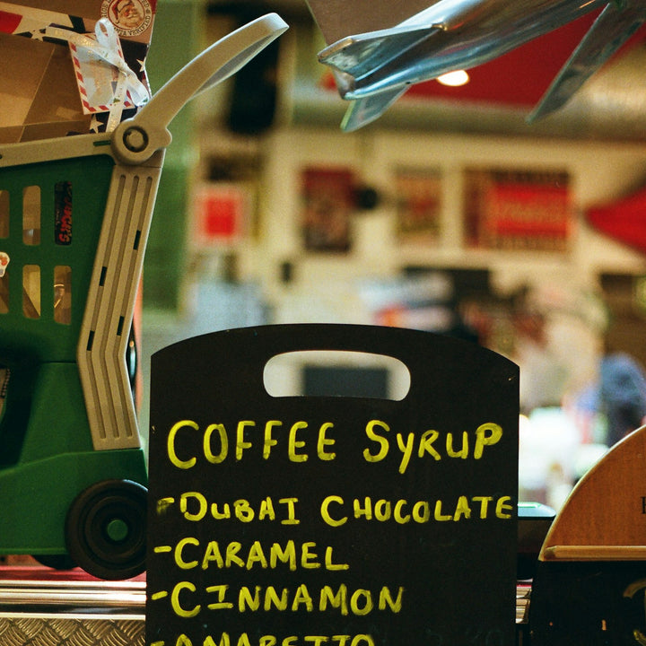 A cafe chalkboard menu listing coffee drinks and syrup flavors