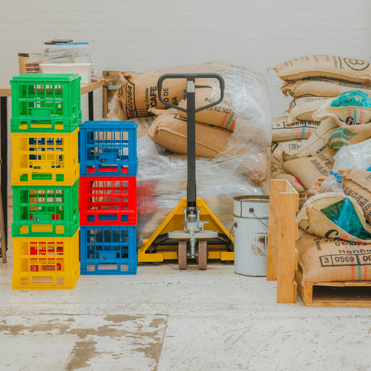 Burlap coffee sacks stacked with crates on a warehouse pallet jack in import storage