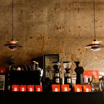 Bags of roasted coffee and two grinders on a specialty coffee shop counter