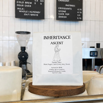 Bag of ASCENT by Inheritance coffee on a cafe counter by the grinder, roasted by Inheritance Coffee in Pensacola, FL for home brewers and cafes