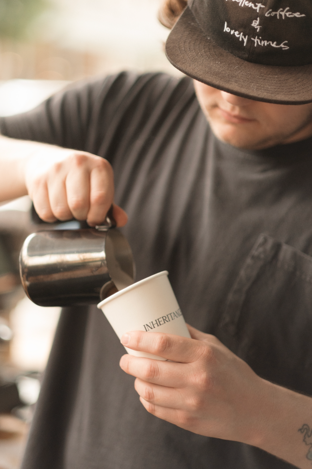 barista uses milk pitcher to pour latte into Inheritance Coffee cup