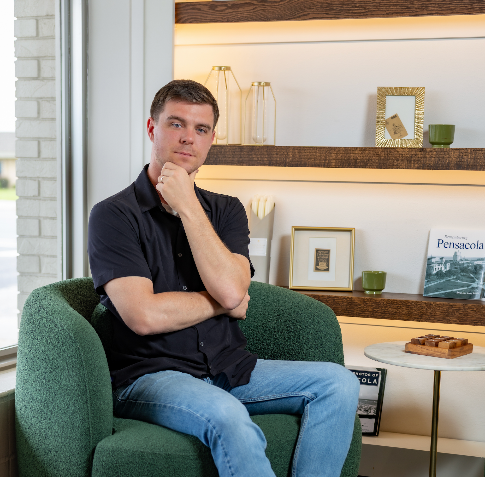 Man sitting in a green armchair in a modern living room.