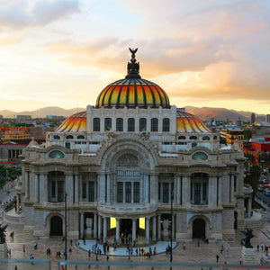 Palacio de Bellas Artes at sunset with a cityscape in the background