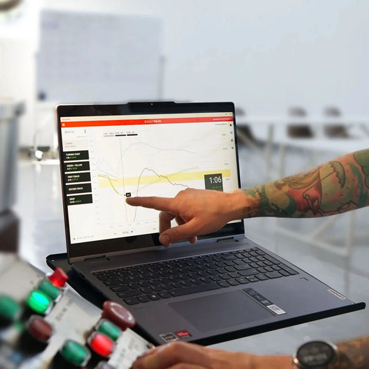 Person pointing at a laptop screen displaying a software interface in an industrial setting.